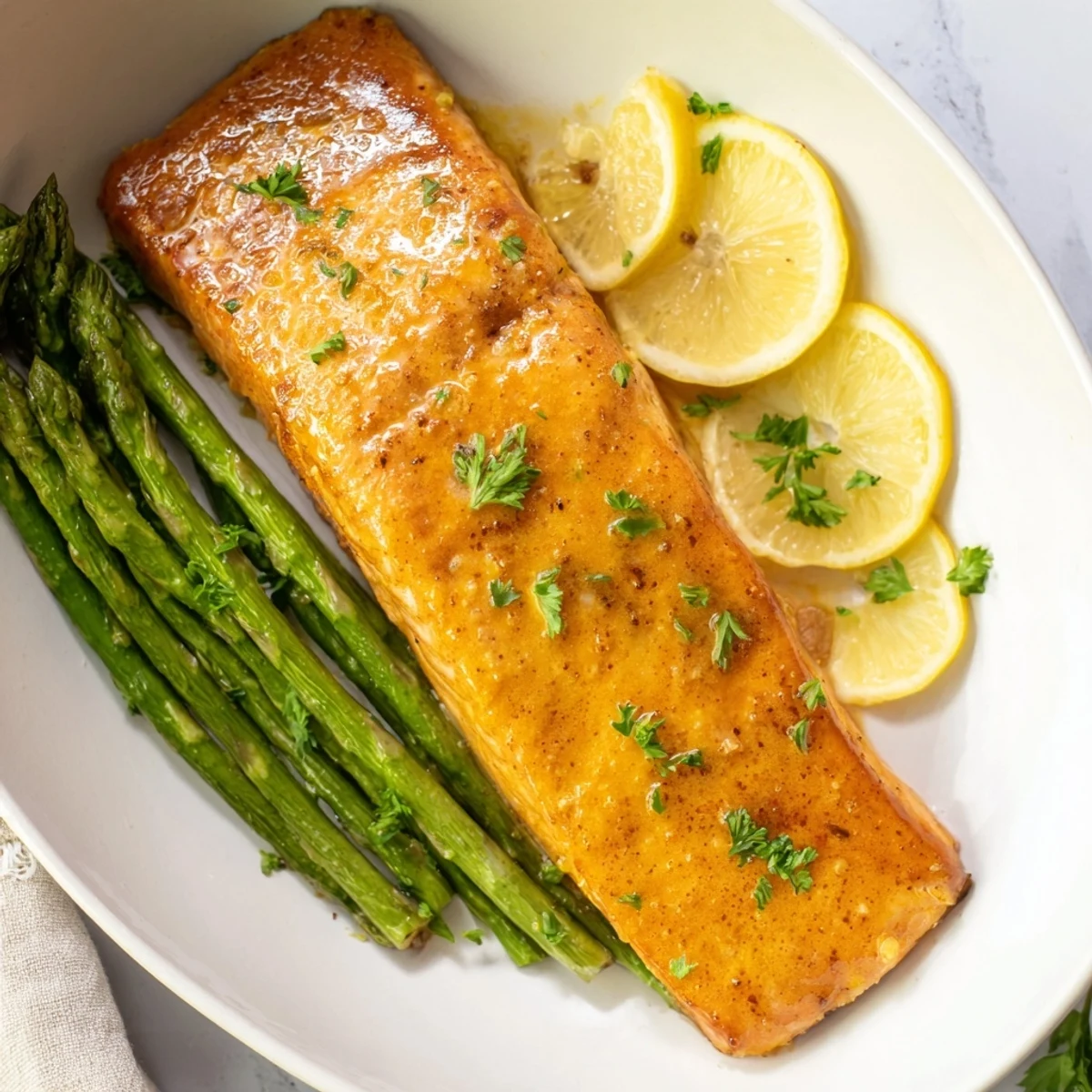 Skillet Lemon-Butter Salmon, glistening, is served atop vibrant asparagus, ready for a delicious dinner.
