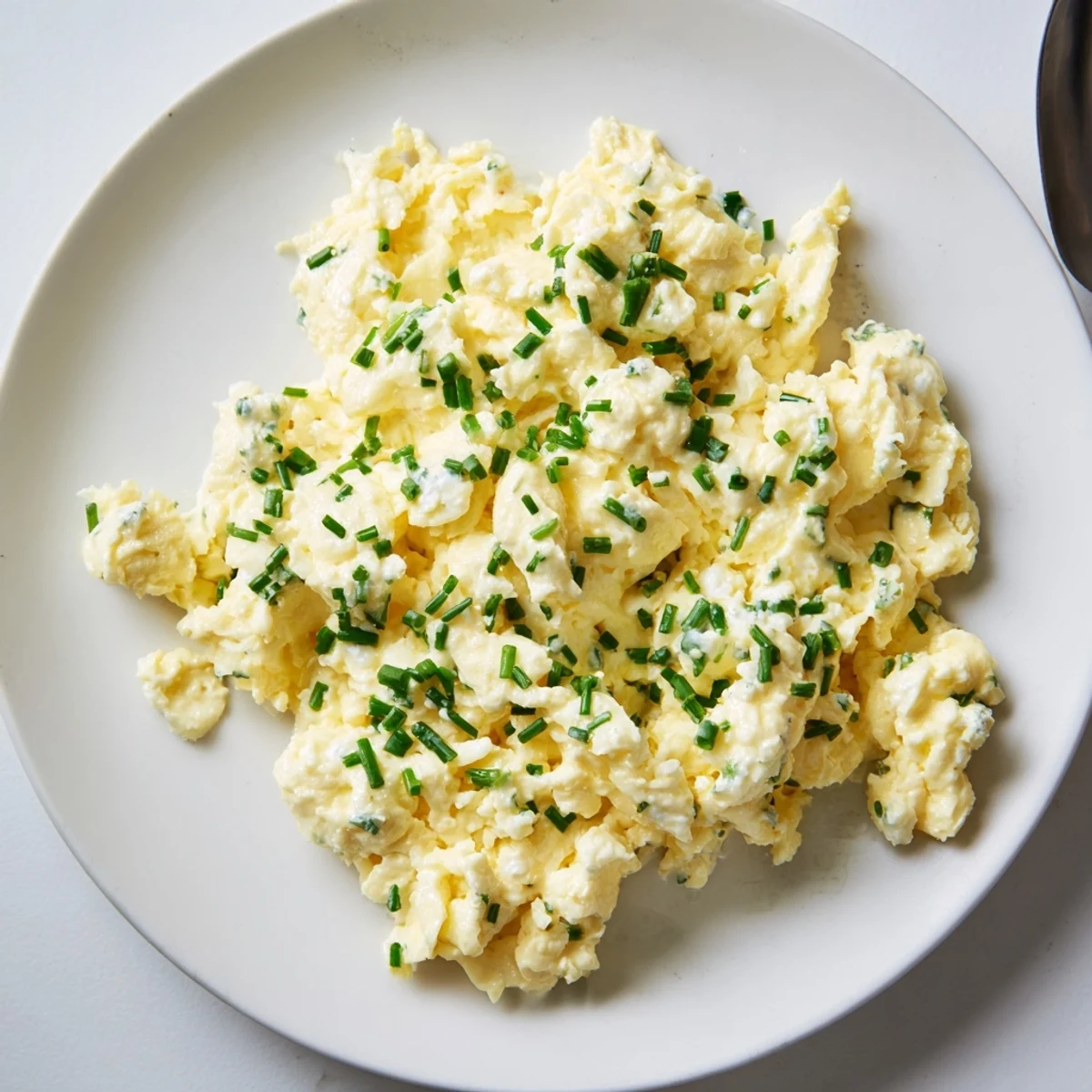 Fluffy Cottage Cheese Scrambled Eggs, a golden breakfast, ready to serve with fresh herbs.