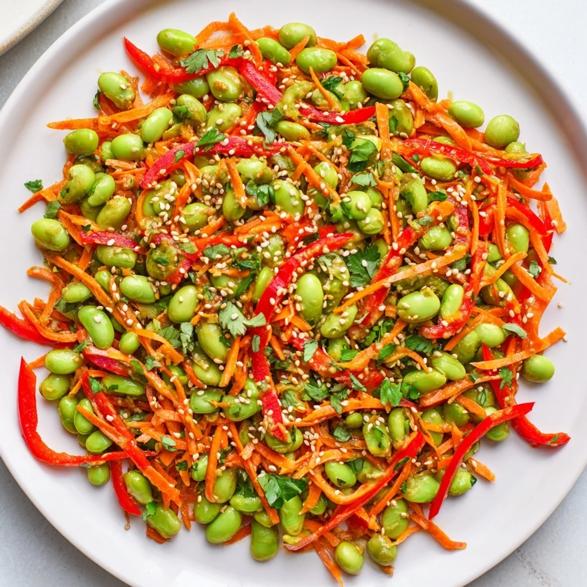 Freshly tossed Asian Edamame Salad: a vegan delight with colorful veggies and crunchy toasted sesame seeds inside.