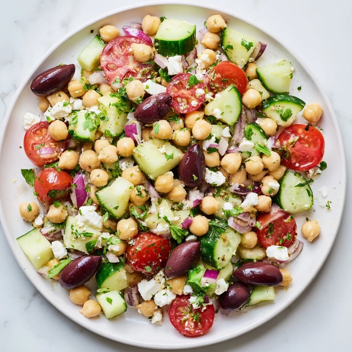 Freshly tossed Mediterranean chickpea salad, showing a vibrant mix of vegetables and a zesty lemon dressing.