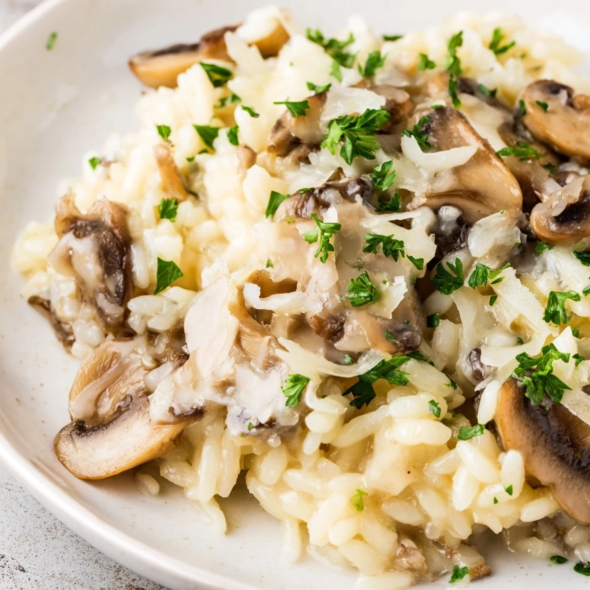 Close-up of a serving of orzo mushroom risotto-style, highlighting the creamy consistency and savory garnishes on a rustic plate.