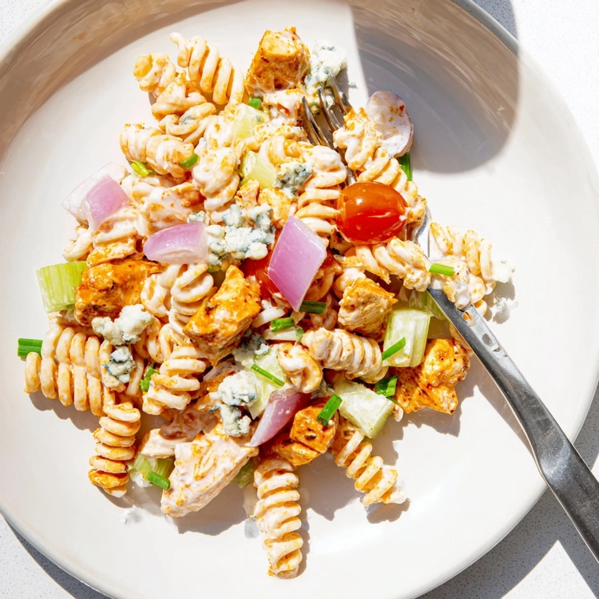 Freshly tossed cold buffalo chicken pasta salad featuring tender shredded chicken, rotini noodles, cherry tomatoes, and a zesty tangy dressing.  
