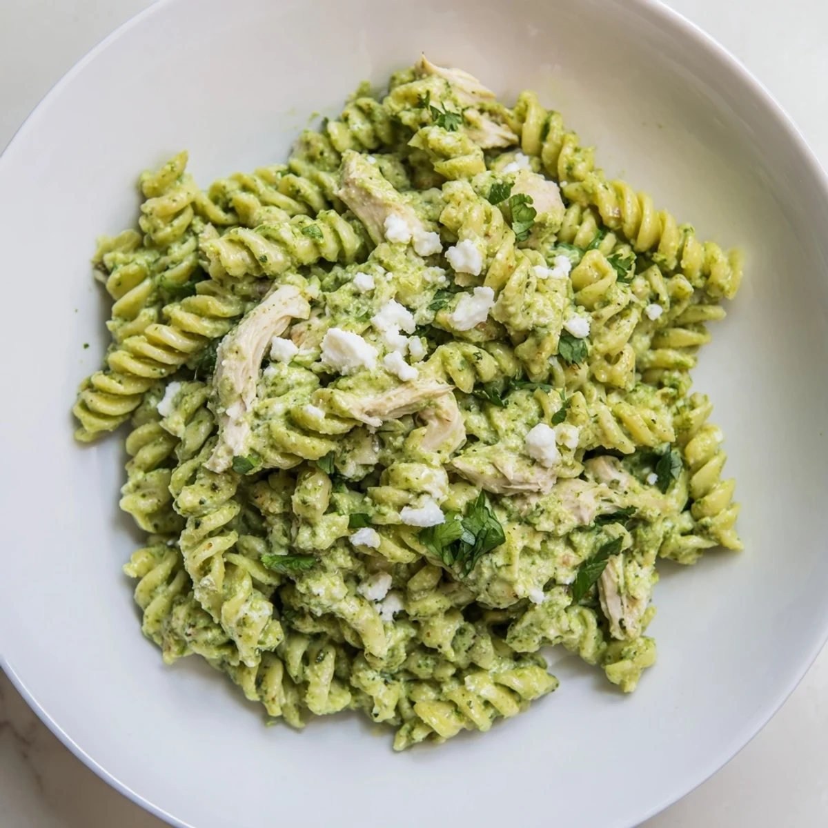 A close-up photo of Cilantro Lime Chicken Pasta, showcasing creamy green sauce coating rotini and tender shredded chicken. 