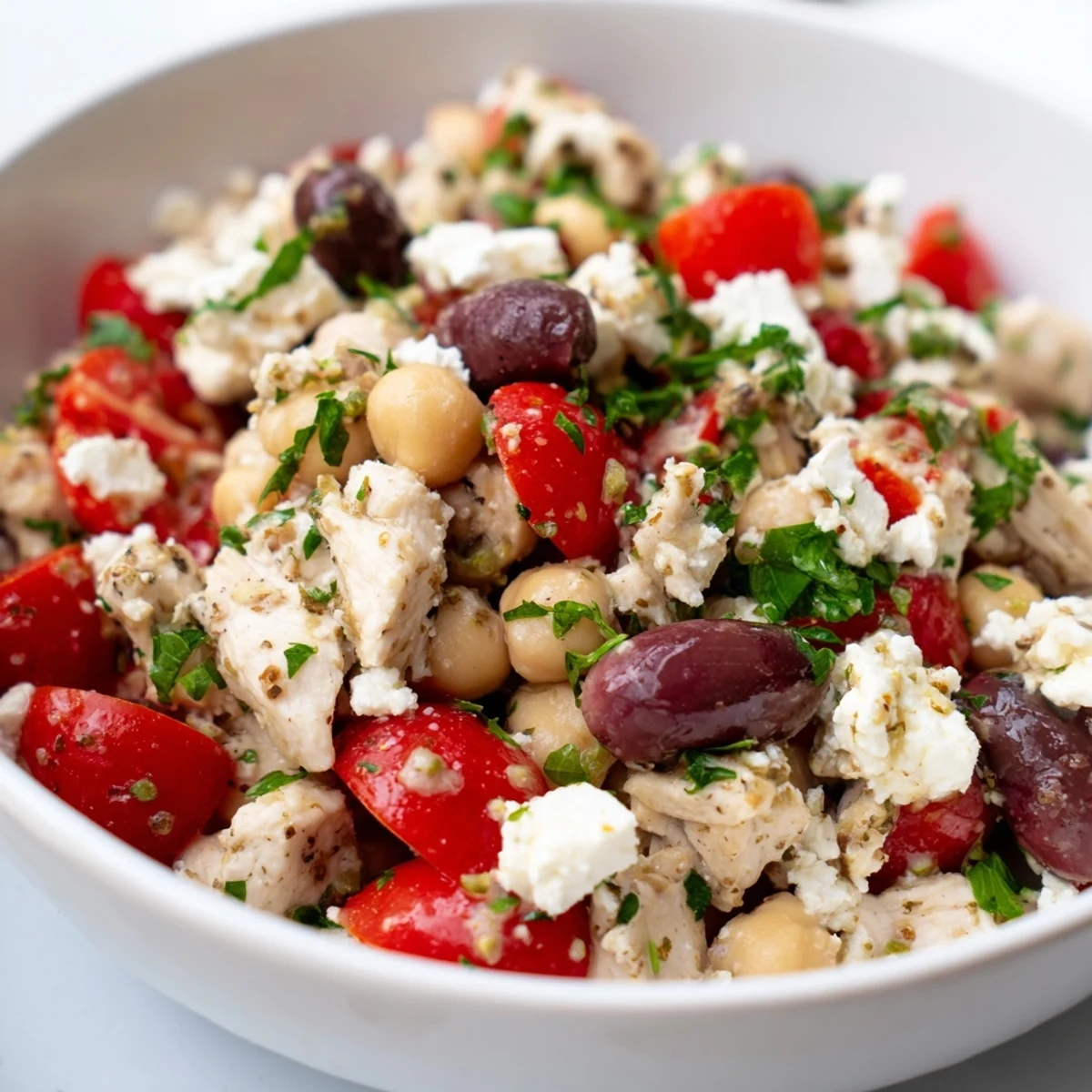 Fresh Mediterranean Chickpea Chicken Salad with feta, Kalamata olives, and cherry tomatoes on a white platter.