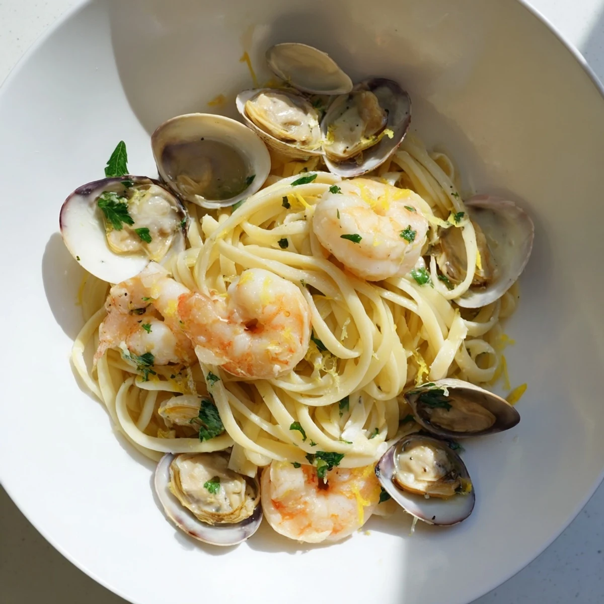 This bowl of Seafood Linguine features tender shrimp and mussels over linguine, with lemon wedges and a side of crusty bread.