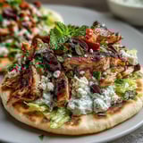 Juicy oregano-marinated chicken thighs sizzling in a skillet next to a bowl of cool, tangy cucumber feta tzatziki sauce. 