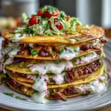 Layered taco dip cups with creamy beans, fresh veggies, and melted cheese, served in clear cups for a colorful appetizer spread.