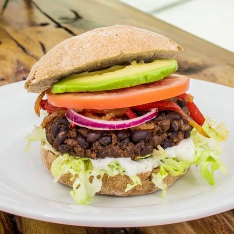A close-up of a plate with a homemade Zesty Black Bean Burger, showcasing fresh ingredients.