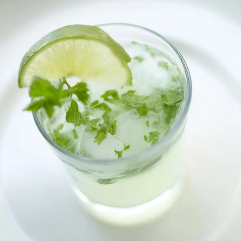Bright green Mint Lime Agua Fresca in a pitcher, garnished with fresh lime slices, so cool.