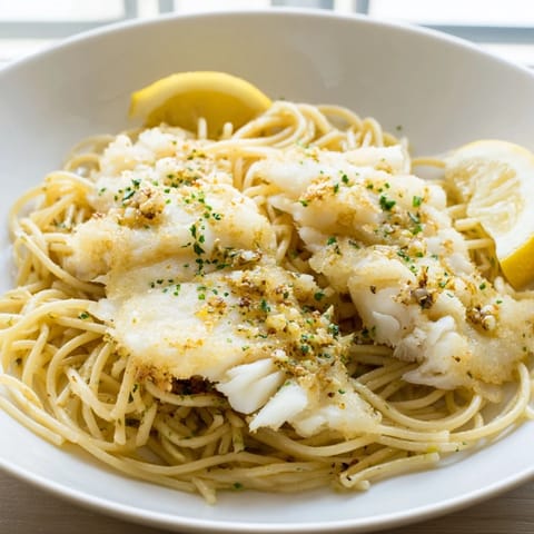 Flaky pan-fried fish mixed with bright lemon pasta, topped with parsley and chives for a fresh finish.