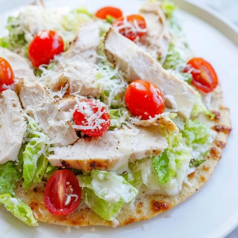 A close-up of Caesar Chicken Flatbread with juicy grilled chicken, crisp romaine, and creamy Parmesan topping.