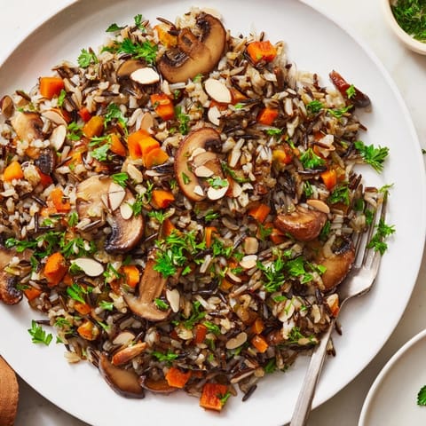 Hearty vegetarian side dish featuring tender wild rice and golden-brown sautéed mushrooms, served warm in a rustic bowl.