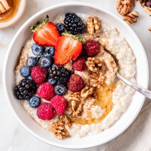 Creamy millet porridge topped with mixed berries, nuts, and seeds in a cozy breakfast bowl.  