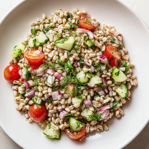 Colorful Barley and Herb Salad with diced cucumber and red onion, served in a white ceramic bowl.  
