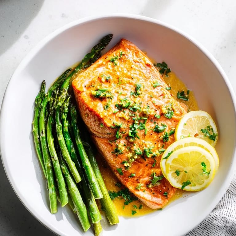 A close-up of beautifully cooked Skillet Lemon-Butter Salmon with asparagus, showcasing golden skin and lemon sauce.