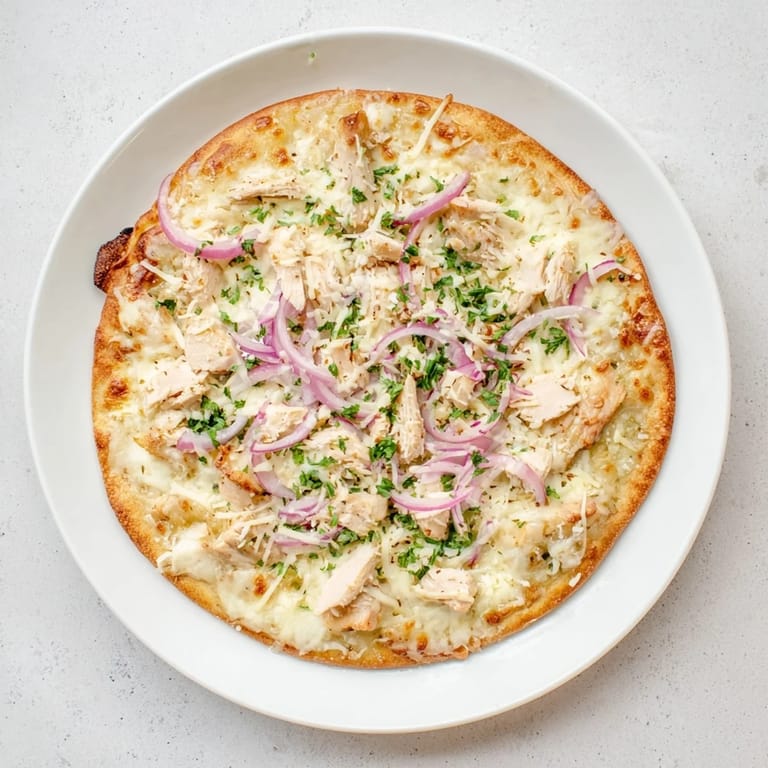 Two slices of Chicken Alfredo Pizza on a wooden board, topped with melted mozzarella and fresh parsley.